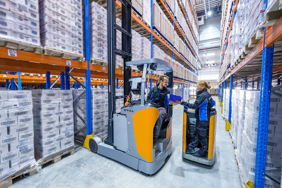 Zwei Mitarbeiter auf Flurföderfahrzeuge in der Logistikhalle