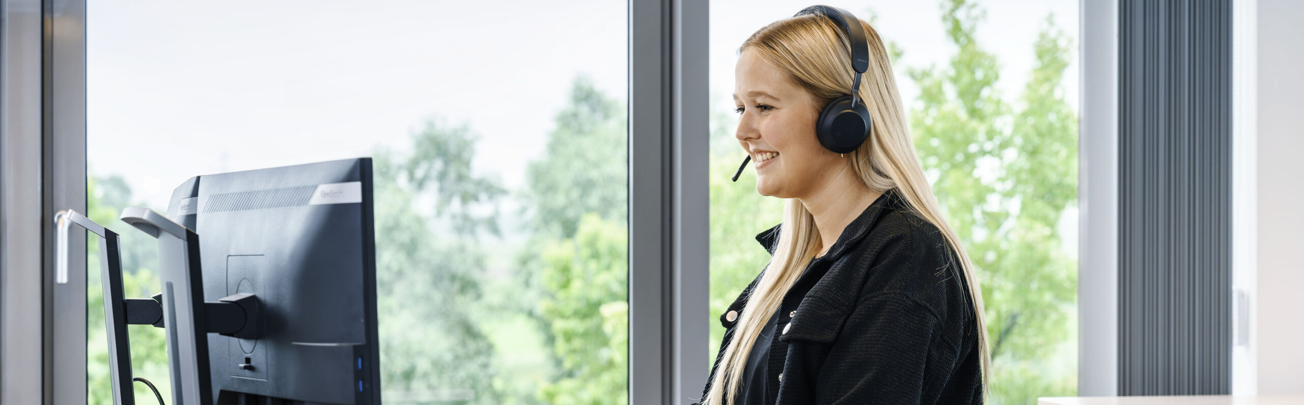 Mitarbeiterin am Arbeitsplatz mit Headset
