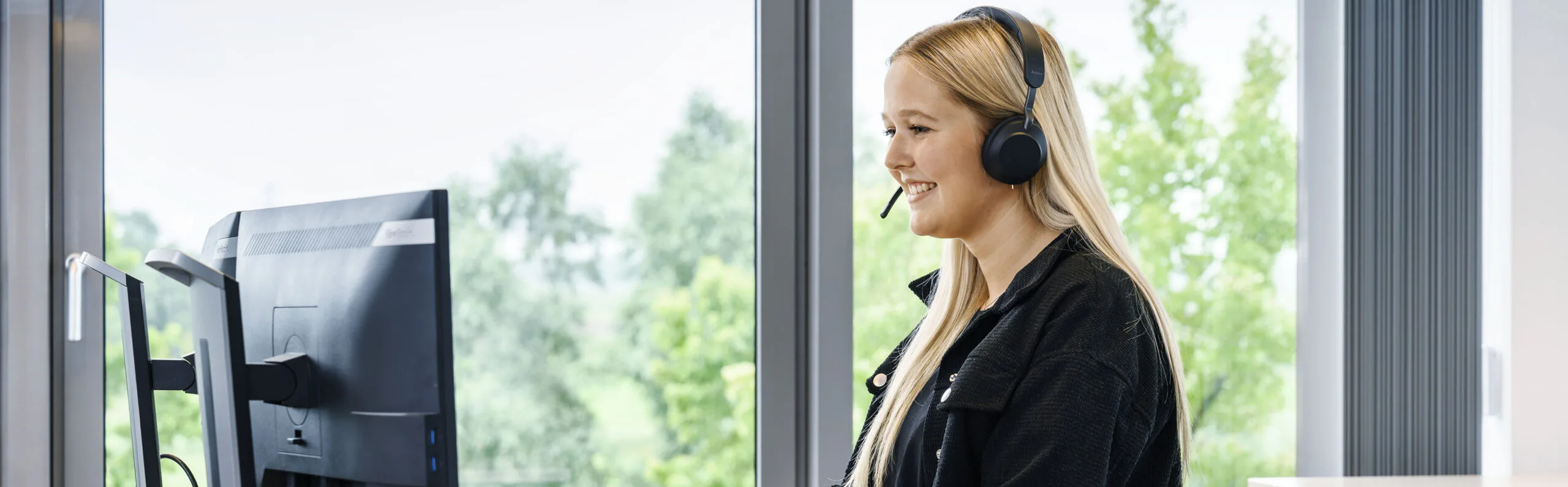 Mitarbeiterin am Arbeitsplatz mit Headset